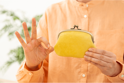 財布を持ってオッケーのハンドサインをする人